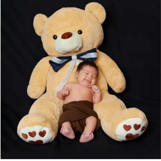 Recién nacido junto a un oso de peluche